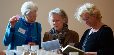 Three older women reading the programme at a coffee table