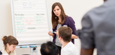 Young woman presenting results on a flip chart to a group