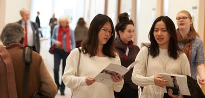 Two young women reading the convention brochure in a foyer