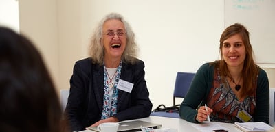 A laughing laureate next to a young woman at a round table