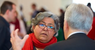 Woman with glasses and a red scarf listening to a man