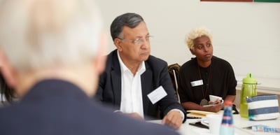 Man in a suit and a young woman with bleached hair listening at a table