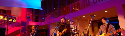 Band performing on a stage lit in blue and red