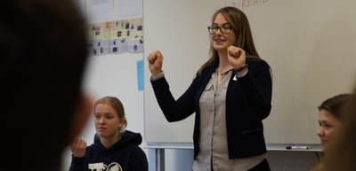 A young woman gesturing while speaking in front of a group