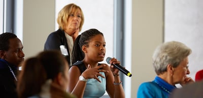 Young woman speaking into a microphone in a discussion group