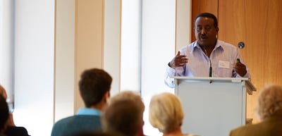 Man speaking at a lectern to a seminar group