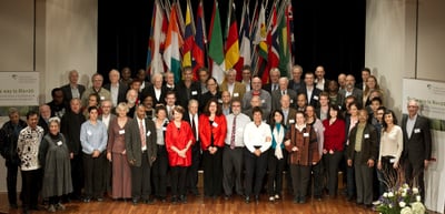 Group photo of the participants of the 1st convention on a stage in front of national flags