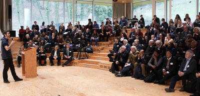 A student with a microphone opening the Young Talents Day in front of a full auditorium