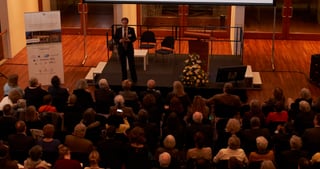 Speaker on the stage of the Konzerthaus Freiburg in front of a full audience