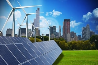 Solar panels and wind turbines on a green meadow in front of a city skyline