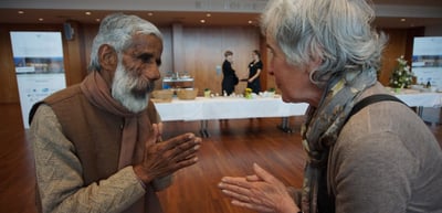An elderly man and a woman greeting each other with folded hands