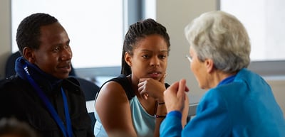 Young woman listening to an older woman, a young man next to them