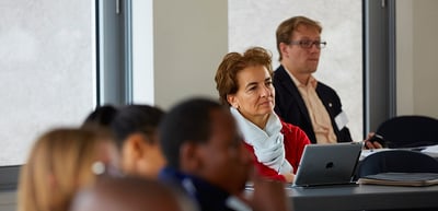 Participants with laptops listening at a seminar table