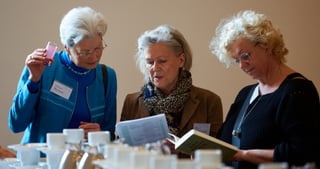 Three women looking at a programme booklet at a breakfast table