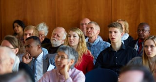 Audience seated in rows in a room with wood panelling