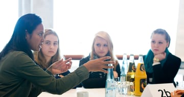 A laureate talking with three students at a table