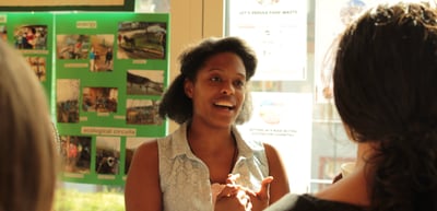 Smiling young woman talking at an exhibition stand with photo posters