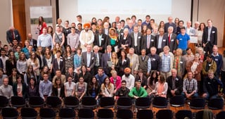 Group photo of a large number of participants in a hall with rows of chairs