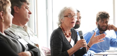 A woman speaking into a microphone in a discussion round