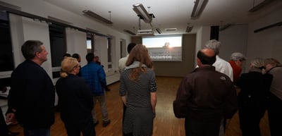 Guests standing in a room in front of a projection screen