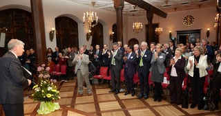 Standing ovation in a historic hall with chandeliers during the opening ceremony
