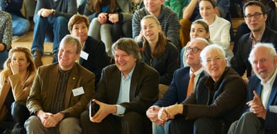 Smiling audience seated on steps and benches
