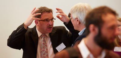 Man scratching his head during a lively conversation with other participants