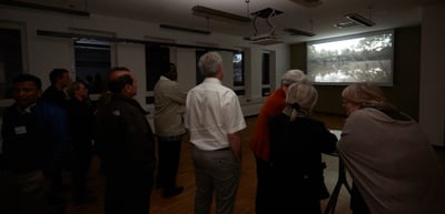 Guests standing in a room in front of a projected film still