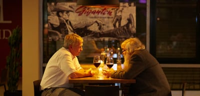 Two people talking over wine at a candlelit table in a restaurant