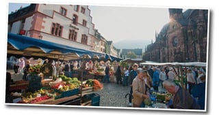Farmers' market on the Cathedral Square in Freiburg with stalls of fruit and vegetables and the cathedral