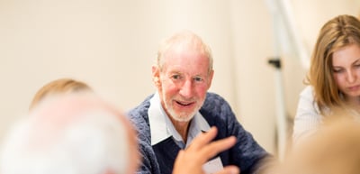 Smiling older man gesturing during a conversation at a table