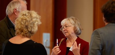 Older woman with glasses talking with other participants