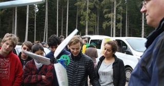 Teenagers holding a self-built wind turbine rotor blade in a forest