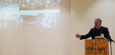 A man speaking at a lectern with the logo UWC Robert Bosch College