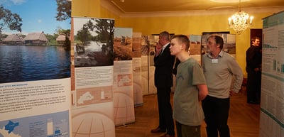 Participants looking at an exhibition of poster boards in a historic room with a chandelier