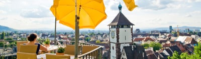 Terrace with yellow parasols above the rooftops of Freiburg and the Schwabentor city gate