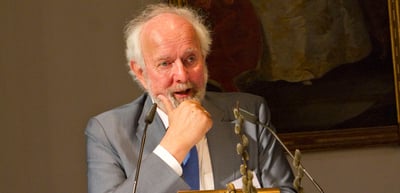Older man with white hair listening thoughtfully, his hand at his chin