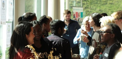 Young people and adults talking with drinks in a crowded room