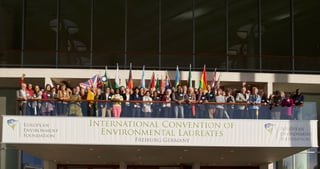 Participants with national flags on a balcony above a banner reading International Convention of Environmental Laureates, Freiburg Germany