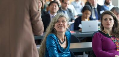 Two women in the audience listening, one smiling and looking up