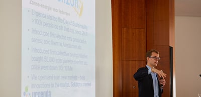 Young man presenting next to a projected slide of Urgenda