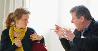 Young woman with a yellow scarf and a man gesturing in a lively conversation