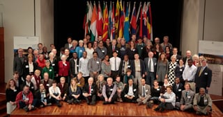 Group photo of the participants of the 5th convention on a stage in front of national flags