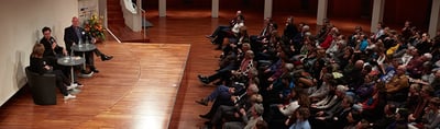 Podium talk on the stage of a large hall with a full audience