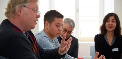 A laureate explaining something to students at a round table