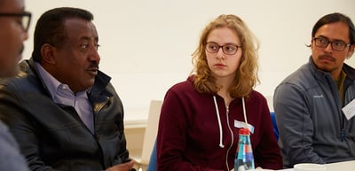 A laureate and two students listening at a round table