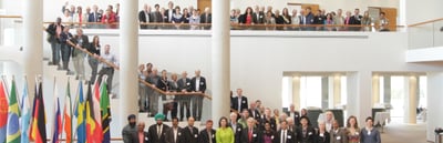 Group photo of the convention participants on the stairs and the gallery of a hall with national flags