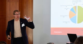 Man presenting in front of a projected pie chart