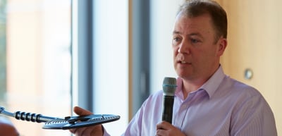 Man speaking into a handheld microphone during a discussion