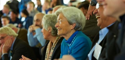 Smiling older woman with glasses in a laughing audience